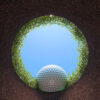 Looking out of a golf hole at a golf ball ready to drop inside.